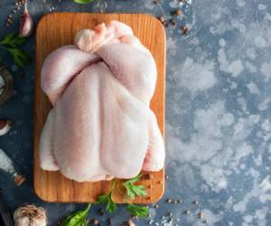 Whole raw chicken on a wooden board with spices for cooking, top view, horizontal, copy space