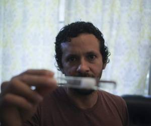 Panamanian researcher Dumas Galvez holds a test tube with live ants at his house in Panama City, on May 12, 2020. - 38-year-old researcher Dumas Galvez, a Smithsonian post-doctorate laureate, had to take all his research material, including thousands of ants, to the bathroom of his house due to the mobility restrictions imposed amid the new coronavirus pandemic. Dumas researches on behavior changes and analyzes how different fungae affect ants. (Photo by MAURICIO VALENZUELA / AFP)