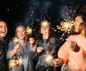 Four happy women holding sparklers, throwing confetti