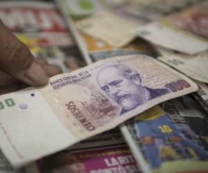 <i>ARCHIVO. El propietario de un quiosco cuenta billetes de pesos argentinos en Buenos Aires el 24 de enero de 2014 . AFP FOTO / LEO LA VALLE</i>