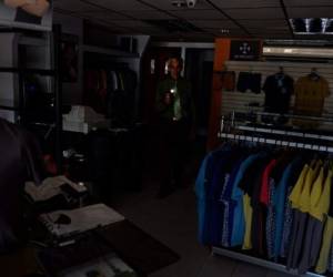 Un vigilante revisa una tienda de ropa durante uno de los cortes de energía en San Cristobal, Táchira, una de las regiones afectadas por los prolongados cortes de energía. Foto AFP.