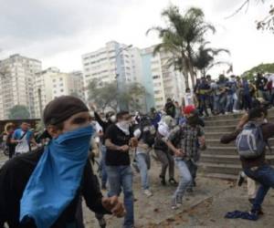 Opposition activists clash with riot police in Caracas on April 10, 2017. Venezuela's political crisis intensified last week when the Supreme Court issued rulings curbing the powers of the opposition-controlled legislature. The court reversed the rulings days later, but the opposition intensified its protests from that moment. / AFP PHOTO / FEDERICO PARRA