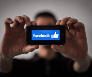 (FILES) In this file photo taken on January 15, 2019 a man shows the logo of social network Facebook displayed on a smartphone in Nantes, western France. - Facebook said January 31, 2019 it took down hundreds of accounts from Iran that were part of a vast manipulation campaign operating in more than 20 countries. The world's biggest social network said it removed 783 pages, groups and accounts 'for engaging in coordinated inauthentic behavior tied to Iran.' (Photo by LOIC VENANCE / AFP)