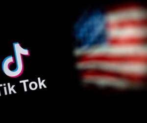 (FILES) In this file photo illustration, the social media application logo, TikTok is displayed on the screen of an iPhone on an American flag background on August 3, 2020 in Arlington, Virginia. - President Joe Biden on June 9, 2021 revoked executive orders from his predecessor Donald Trump seeking to ban Chinese-owned mobile apps TikTok and WeChat over national security concerns, the White House said. A White House statement said that instead of banning the popular apps, the Biden administration would carry out a 'criteria-based decision framework and rigorous, evidence-based analysis to address the risks' from internet applications controlled by foreign entities. (Photo by Olivier DOULIERY / AFP)