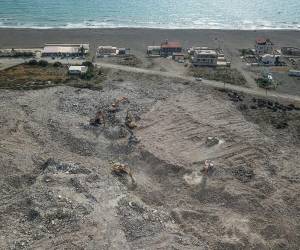 <i>Esta fotografía aérea tomada el 9 de julio de 2023 muestra excavadoras trabajando en un vertedero junto a una playa en Samandag, en el sur de la provincia de Hatay. La excavadora destrozó los restos del edificio dañado en el sureste de Turquía, derribándolos en una nube de polvo, la última amenaza que enfrentan los sobrevivientes del mortal terremoto de febrero que devastó la región. Extendiéndose hasta el horizonte, un capullo de fino polvo gris envuelve la ciudad de Samandag, en el sur de la provincia de Hatay, que fue devastada por el terremoto del 6 de febrero que mató a más de 55.000 personas y arrasó partes de Turquía y Siria.OZAN KOSE / AFP</i>