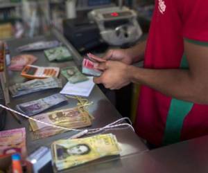 A Brazilian shopkeeper counts Venezuelan money received from Venezuelans crossing the border to buy food at Pacaraima, Roraima, Brazil, on February 27, 2018. - According to local authorities, around one thousand refugees are crossing the Brazilian border each day from Venezuela. With the constant influx of Venezuelan immigrants, most are living in shelters and the streets of Boa Vista and Pacaraima cities, looking for work, medical care and food. Most are legalizing their status to stay and live in Brazil. (Photo by Mauro Pimentel / AFP) / TO GO WITH AFP STORY by Paula RAMÓN