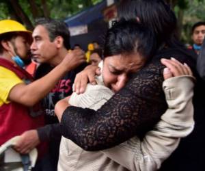 Miembros de la familia de María Ortiz, que murió en el terremoto de la Ciudad de México se abrazan el 22 de septiembre de 2017. AFP PHOTO / Pedro Pardo