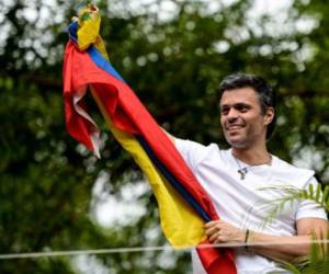 Venezuelan opposition leader Leopoldo Lopez displaying a Venezuelan national flag, greets supporters gathering outside his house in Caracas, after he was released from prison and placed under house arrest for health reasons, on July 8, 2017.Venezuela's Supreme Court confirmed on its Twitter account it had ordered Lopez to be moved to house arrest, calling it a 'humanitarian measure' granted on July 7 by the court's president Maikel Moreno. 'Leopoldo Lopez is at his home in Caracas with (wife) Lilian and his children,' Lopez's Spanish lawyer Javier Cremades said in Madrid. 'He is not yet free but under house arrest. He was released at dawn.' / AFP PHOTO / Federico PARRA