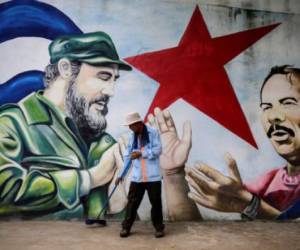 A municipal worker sweeps the floor in front of a mural depicting Cuban revolutionary leader Fidel Castro (L) and Nicaraguan President Daniel Ortega at Cuba square in Managua on November 26, 2016, the day after Castro died. Cuban revolutionary leader Fidel Castro has died aged 90, prompting mixed grief and joy Saturday along with international tributes for the man whose iron-fisted rule defied the United States for half a century. / AFP PHOTO / INTI OCON