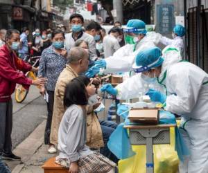 (FILES) This file photo taken on May 15, 2020 shows medical workers taking swab samples from residents to be tested for the COVID-19 coronavirus in a street in Wuhan in China's central Hubei province. - Chinese authorities have completed a mass coronavirus testing campaign in Wuhan, finding only 300 positive results among nearly 10 million people in the city where the pandemic began, local officials said on June 2, 2020. (Photo by STR / AFP) / China OUT