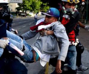 An opposition demonstrator wounded during clashes with riot police is carried away by medics during a protest against Venezuelan President Nicolas Maduro, in Caracas on June 26, 2017. A political and economic crisis in the oil-producing country has spawned often violent demonstrations by protesters demanding Maduro's resignation and new elections. The unrest has left 75 people dead since April 1. / AFP PHOTO / FEDERICO PARRA