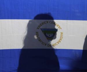 The silhouette of a woman is seen through a Nicaraguan flag during a field Mass held by the Catholic Church in favor of peace in Nicaragua, in Managua on January 1, 2019. (Photo by INTI OCON / AFP)