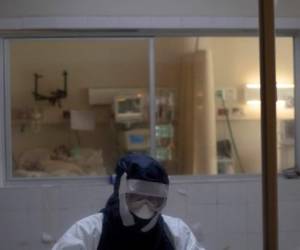 Una doctora permanece en la cabina de observación frente a un paciente infectado con coronavirus, en la unidad de cuidados intensivos en el Hospital San Rafael, Santa Tecla, La Libertad. (Foto Yuri CORTEZ / AFP)