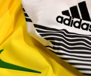 (FILES) This file photo taken on April 25, 2018 in Paris shows the logo of sports wear manufacturers Nike and Adidas for the FIFA 2018 World Cup football tournament. Although Russia World Cup teams will be as boldly emblazoned with logos as ever, sportswear makers see little hope this year of repeating sales leaps that greeted past tournaments in iconic football nations like Germany and Brazil. / AFP PHOTO / FRANCK FIFE