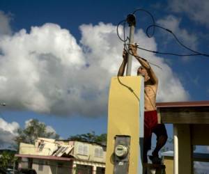 In this Friday, Oct. 13, 2017 photo, a resident tries to connect electrical lines downed by Hurricane Maria in preparation for when electricity is restored in Toa Baja, Puerto Rico. A month after the storm rolled across the center of Puerto Rico, power is still out for the vast majority. (AP Photo/Ramon Espinosa)