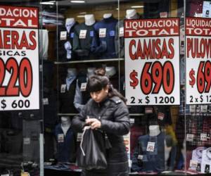 A woman walks past a store offering discounts in Buenos Aires, on August 30, 2019. - Recession-hit Argentina has been whipped by market volatility since business-friendly Argentine President Mauricio Macri was trounced in party primaries three weeks ago by leftist challenger Alberto Fernandez. (Photo by RONALDO SCHEMIDT / AFP)