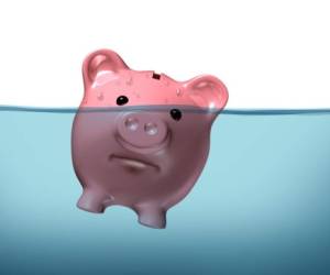 Drowning in debt and keeping your financial head above water represented by a piggy bank pink pig sinking in blue water as a symbol of urgent business and money management failure and defeat.