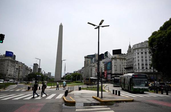 <i>Personas y autobuses pasan por la Avenida 9 de Julio y el Obelisco en Buenos Aires el 13 de diciembre de 2023. FOTO LUIS ROBAYO / AFP</i>