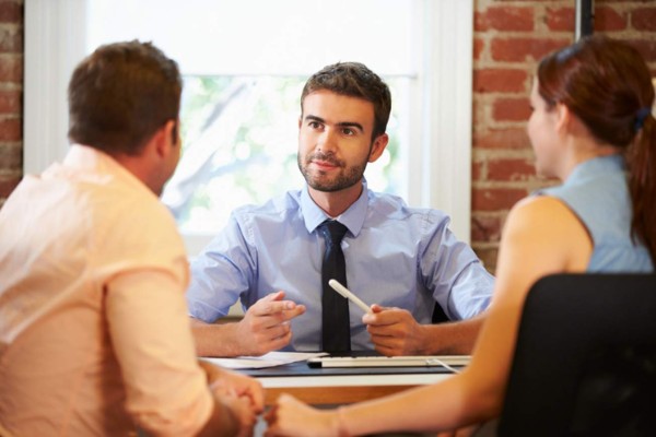 Rear View Of Couple Meeting With Financial Advisor In Office