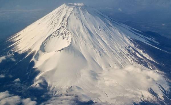 <i>Esta foto tomada el 30 de enero de 2024 muestra una vista aérea del Monte Fuji, la montaña más alta de Japón con 3.776 metros (12.389 pies), desde la ventana de un avión de pasajeros. El 13 de mayo de 2024, las autoridades japonesas anunciaron un sistema de reserva en línea para el sendero más popular del Monte Fuji que intentaba combatir el exceso de turismo en el volcán activo.Richard A. Brooks/AFP</i>