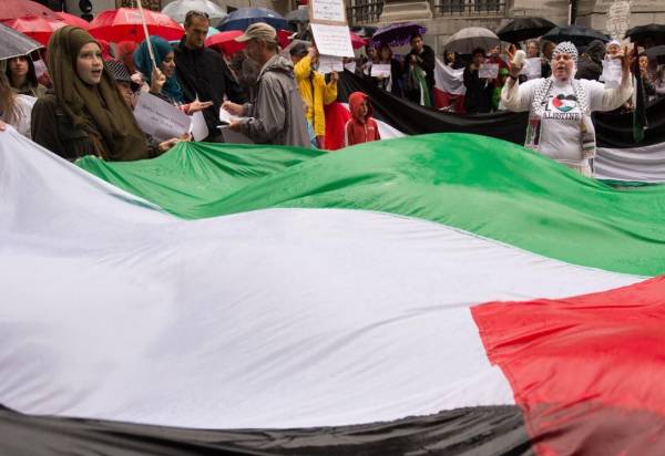 <i>La gente sostiene una bandera palestina gigante mientras participan en una manifestación contra las operaciones militares israelíes en Gaza el 6 de agosto de 2014 frente al Ministerio de Asuntos Exteriores en Bruselas. AFP FOTO/BELGA FOTO BENOIT DOPPAGNE</i>