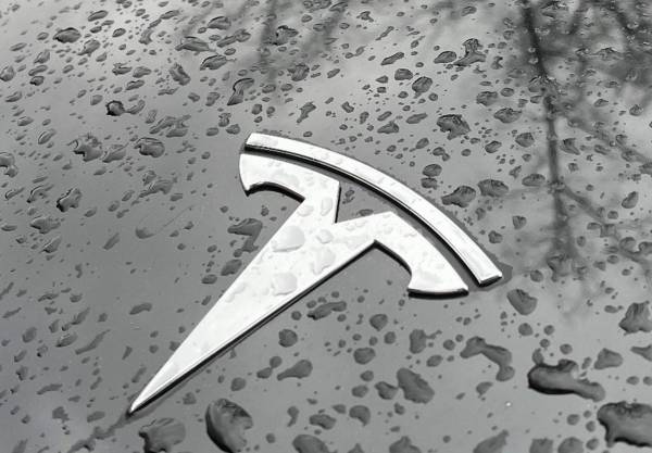 <i>(ARCHIVOS) Se ven gotas de lluvia junto al logotipo de Tesla en el capó de un automóvil eléctrico Tesla en el distrito Kreuzberg de Berlín el 8 de enero de 2023. FOTO David GANNON / AFP</i>