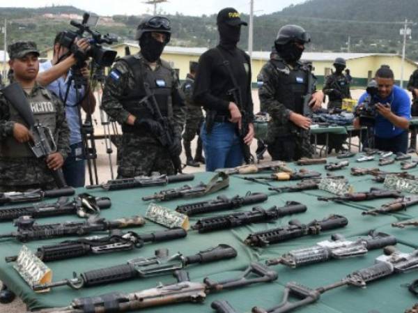 Police and military specialized units personnel custody an assortment of assault rifles and ammo seized to members of the Barrio 18 and Mara Salvatrucha gangs after an operation laubched at the Marco Aurelio Soto national penitentiary in Tamara, 20 km north of Tegucigalpa, on August 29, 2017. / AFP PHOTO / ORLANDO SIERRA