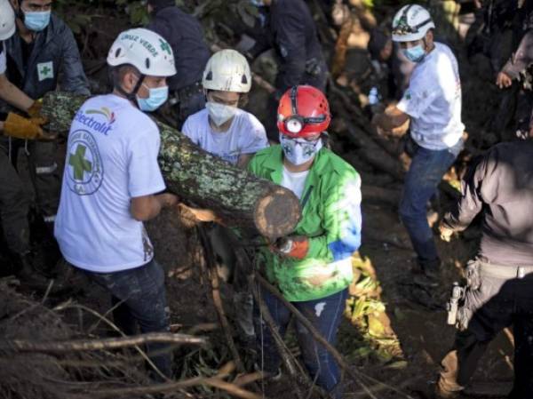 Rescuers of the Green Cross, police and soldiers work to remove rubble while searching for victims of a landslide in Nejapa, El Salvador on October 30, 2020. - A landslide caused by heavy rains left six people dead, 35 disappeared and some 50 homes buried in a rural community of Nejapa, about 15 km north of San Salvador, police reported. (Photo by Yuri CORTEZ / AFP)