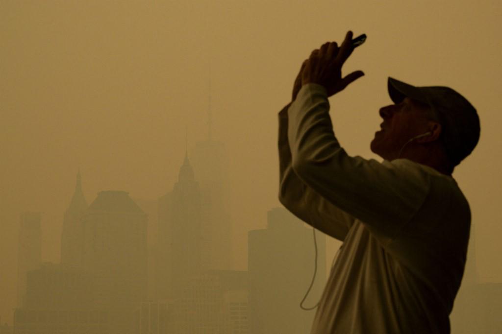 <i>Las personas toman fotos mientras el humo de los incendios forestales en Canadá causan condiciones de niebla en la ciudad de Nueva York el 7 de junio de 2023. El humo de los incendios forestales de Canadá ha envuelto las regiones del noreste y el Atlántico medio de los EE. UU., lo que genera preocupación sobre los daños de la persistente mala calidad del aire . (Foto de ANGELA WEISS / AFP)</i>
