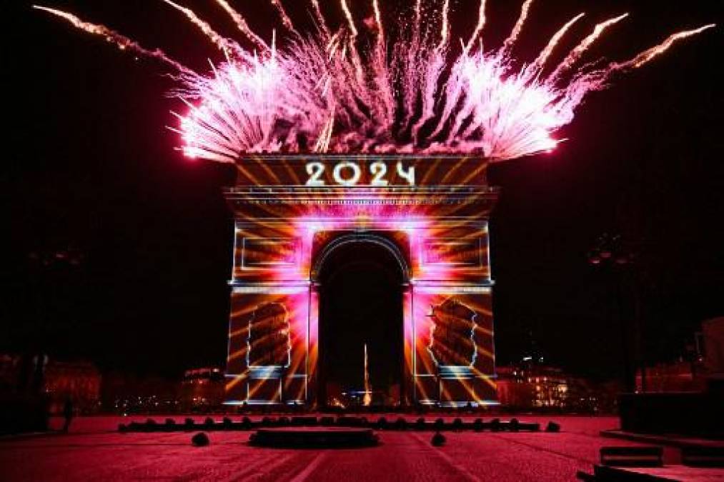 <i>Los fuegos artificiales explotan junto al Arco de Triunfo con la palabra "2024" proyectada, en la Avenida de los Campos Elíseos, durante las celebraciones del Año Nuevo en París, a primera hora del 1 de enero de 2024. (Foto de Bertrand GUAY / AFP)</i>