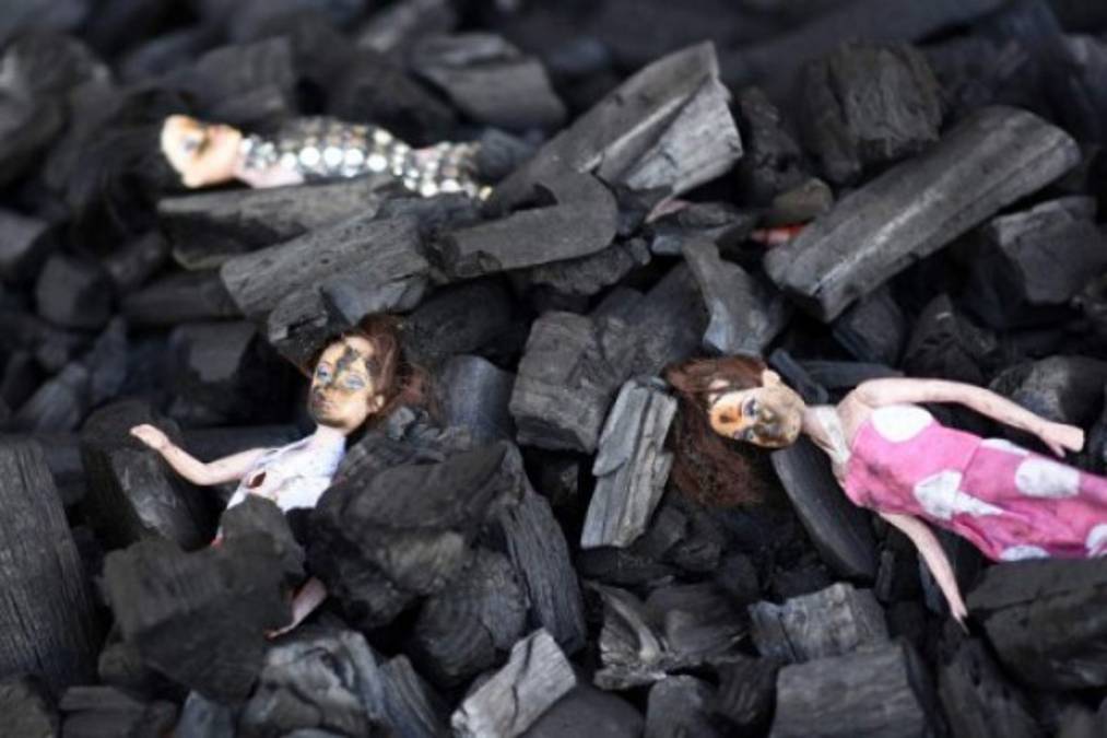 Dolls representing the 29 victims of a fire at government-run children's shelter in San Jose Pinula, east of Guatemala City, are seen amid a pile of carbon as part of a demonstration named 'Guatemala is Not a Safe Place' and performed by artists of the group Project 44 in front of the presidential house in the Guatemalan capital on March 9, 2017.<br/>Medical officials on Thursday raised the toll of girls killed in a fire at a children's shelter in Guatemala to 29 after seven more died from their burns overnight. More than 30 were injured.<br/> / AFP PHOTO / Johan ORDONEZ