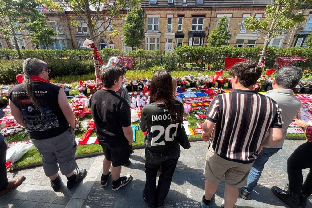 <i>Grupos de personas en un altar improvisado en uno de los laterales del mítico Anfield en el que aficionados del Liverpool han dejado banderas, bufandas, flores y camisetas para honrar este jueves, en la ciudad inglesa a Diogo Jota tras su fallecimiento en un trágico accidente de coche en España. EFE/ Miguel Salvatierra</i>