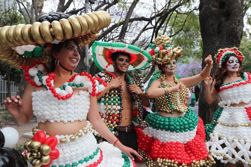 <i>Entre carros alegóricos, matracas, silbatos y globos, familias, turistas y curiosos se detenían a admirar los disfraces y otras expresiones creativas, como figuras de cartón del trofeo mundialista y calaveras con camisetas futboleras. EFE/ Mario Guzmán</i>
