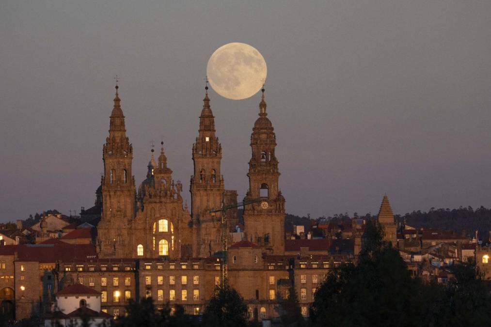 <i>SANTIAGO DE COMPOSTELA, 06/10/2025.- La Luna llena sale sobre la catedral de Santiago, hoy lunes. La primera luna llena del otoño astronómico recibe el nombre de "Luna de la cosecha" o "del cazador". EFE/Lavandeira jr</i>