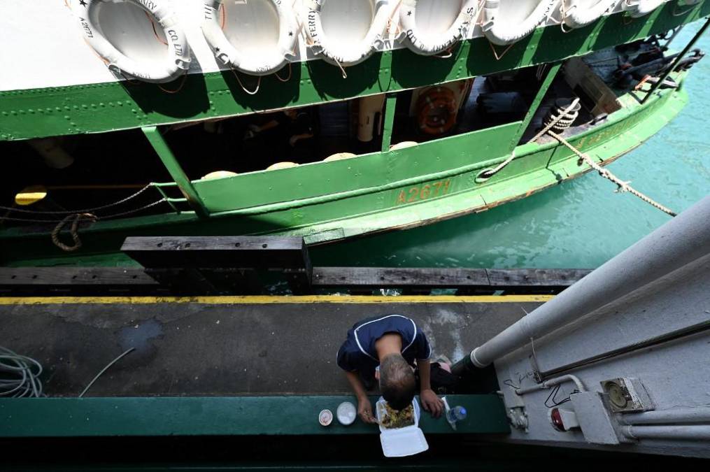 <i>Un empleado de Star Ferry almuerza junto a un ferry en el puerto Victoria de Hong Kong el 4 de mayo de 2022. </i>