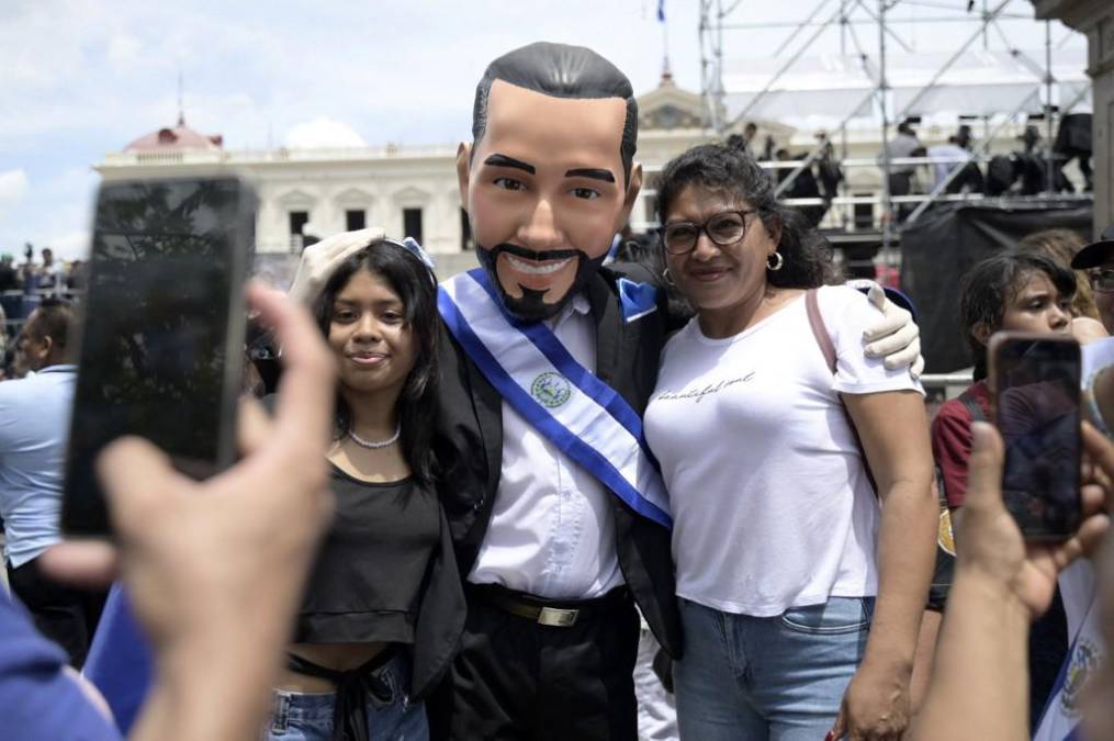 <i>Los partidarios del presidente de El Salvador, Nayib Bukele, posan para una instantánea con un hombre disfrazado de presidente durante su ceremonia de toma de posesión en la plaza Gerardo Barrios, frente al Palacio Nacional, en el centro de San Salvador, el 1 de junio de 2024. (Foto de Daniela RODRIGUEZ / AFP)</i>