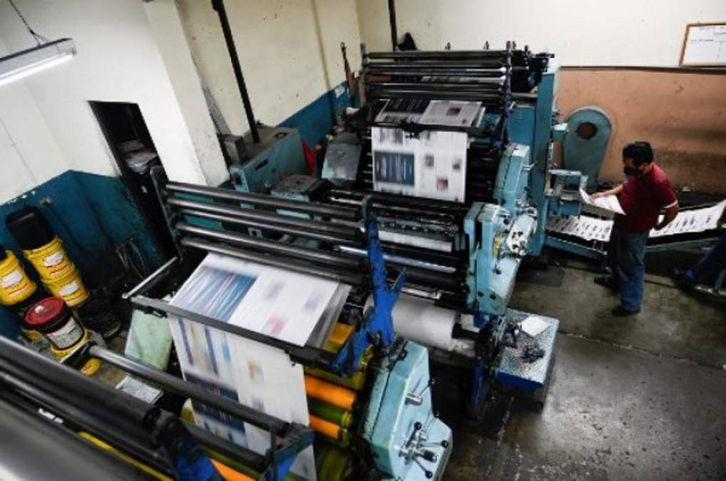 A printing worker checks the last print edition of the newspaper La Hora in Guatemala City on November 12, 2021. - After 101 years, the evening newspaper La Hora de Guatemala printed its last paper edition on Friday, amid the nostalgia of workers and readers. As of Saturday, only an online edition will be avilable. (Photo by Johan ORDONEZ / AFP)