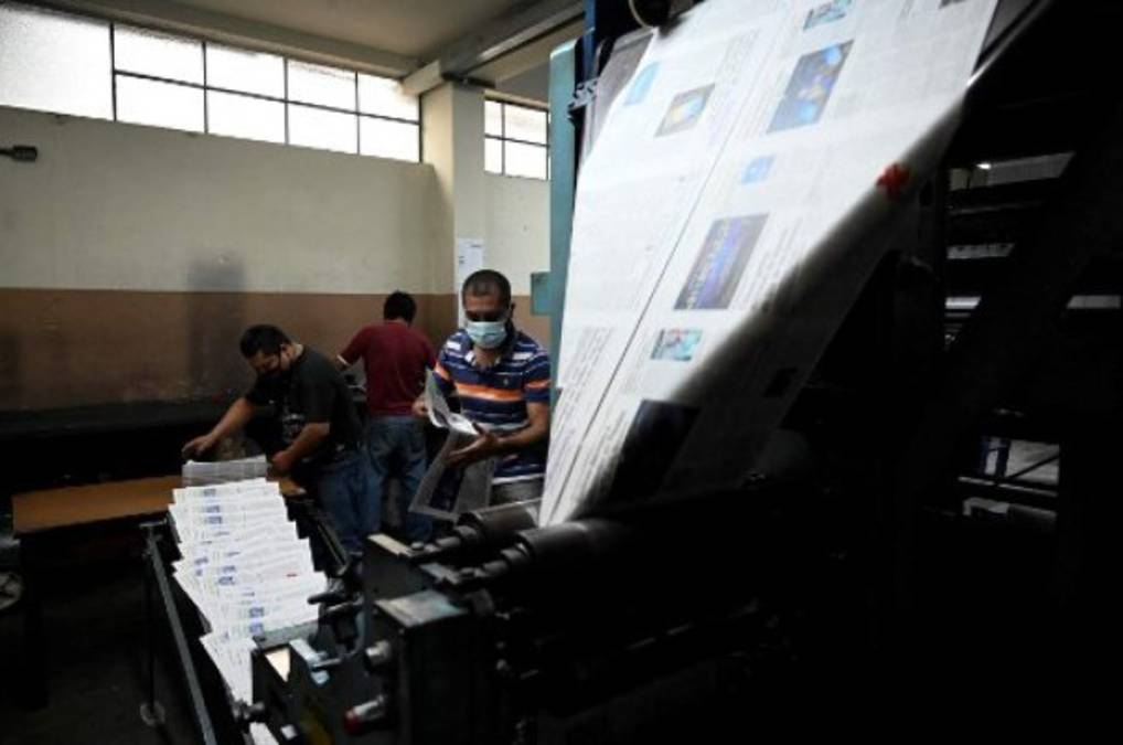 A printing worker places the plates for the last print edition of the newspaper La Hora in Guatemala City on November 12, 2021. - After 101 years, the evening newspaper La Hora de Guatemala printed its last paper edition on Friday, amid the nostalgia of workers and readers. As of Saturday, only an online edition will be avilable. (Photo by Johan ORDONEZ / AFP)