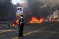 <i>Un activista sostiene un cartel mientras los se observa a automóviles incendiados durante las protestas provocadas por las redadas de inmigración en Los Ángeles, California, EE.UU., 08 de junio de 2025. EFE/ALLISON DINNER</i>