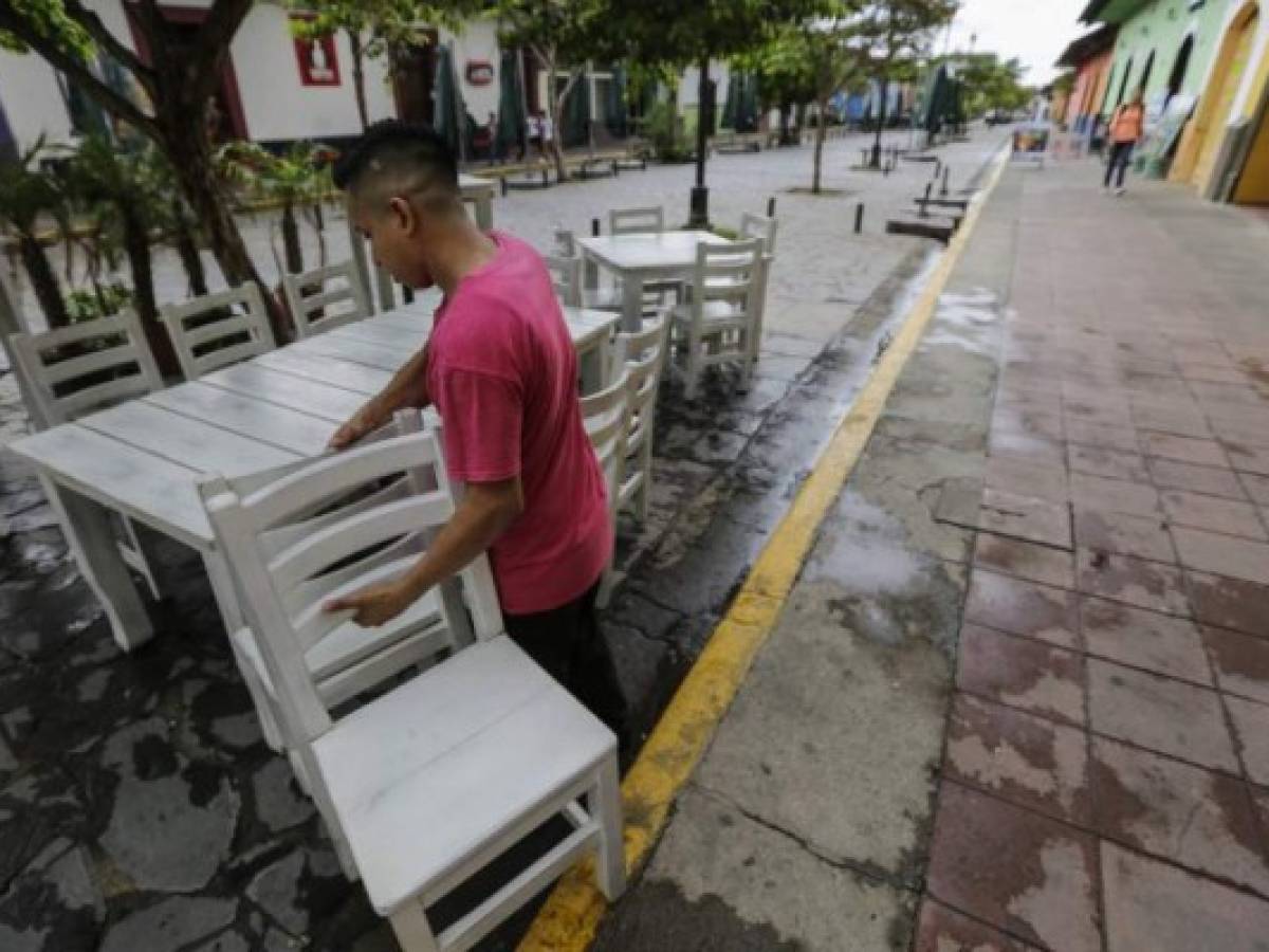 A waiter carries chairs outside an empty restaurant in Granada, 45 km from Managua, on May 22, 2018.Almost all of the tourists have fled from Granada, the so-called 'Paris of Central America', since a wave of protests broke out against the government of Daniel Ortega, leading to pillaging and violent clashes that have left dozens of people dead and wounded. / AFP PHOTO / INTI OCON