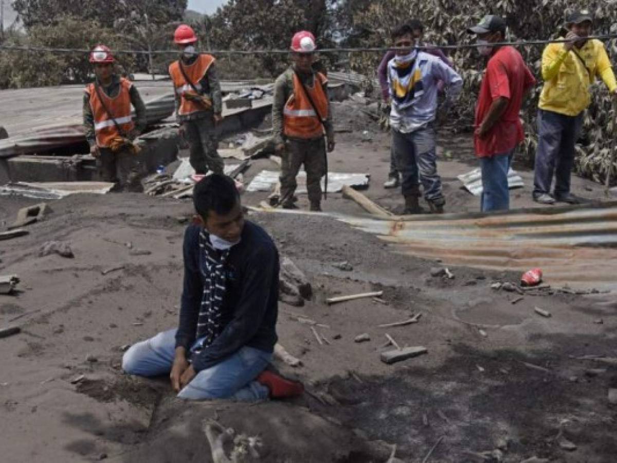 Bryan Rivera, 22, cries as he searches for his relatives, victims of the Fuego Volcano, in the ash-covered village of San Miguel Los Lotes, in Escuintla department, about 35 km southwest of Guatemala City, on June 7, 2018. The threat of fresh landslides forced emergency workers Thursday to suspend a search for victims of a major eruption of Guatemala's Fuego volcano, the country's disaster management agency said. To date, 99 people are known to have died in Sunday's major eruption of the volcano, with nearly 200 more still reported as missing. / AFP PHOTO / JOHAN ORDONEZ