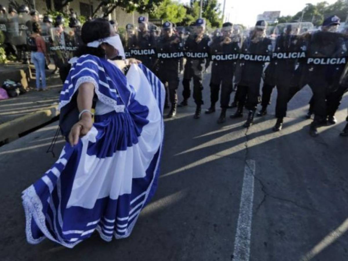 A woman dances in front of a line of riot police blocking a street during a protest against Nicaraguan President Daniel Ortega's government in Managua, on September 13, 2018. / AFP PHOTO / INTI OCON