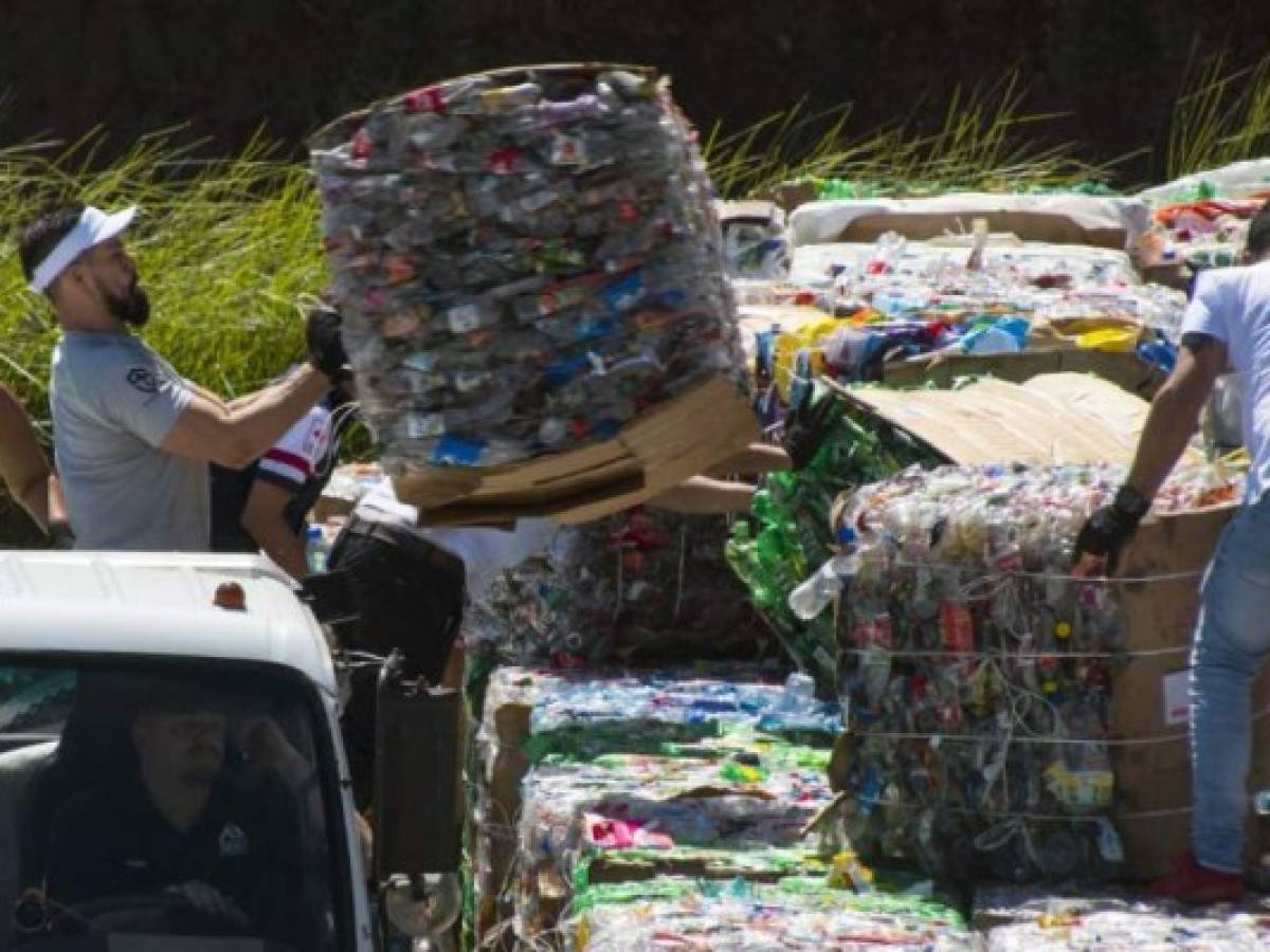 Volunteers help to pile up more than 25 tons of plastic bottles collected for recycling in eight hours, in order to set a Guinness World Record, in Heredia, Costa Rica on December 07, 2018. - According to Ecolones, the organization behind the project, the probative documentation of the process will be send to Guinness World Record and they hope to receive in the next weeks the notification of the acomplishment of the new record, which until now is held by India with 23,539 kg. (Photo by Ezequiel BECERRA / AFP)