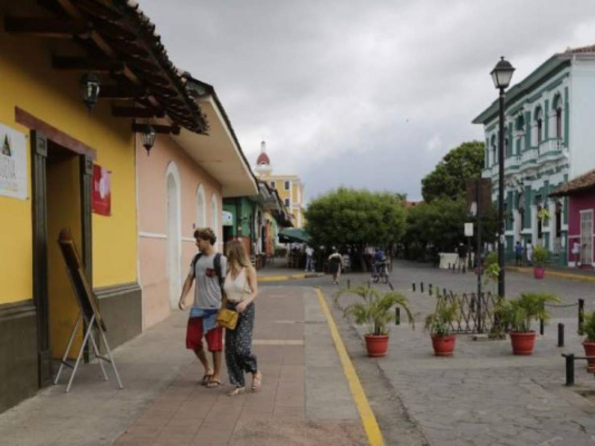 Tourists walk down a street in Granada, 45 km from Managua, on May 22, 2018.Almost all of the tourists have fled from Granada, the so-called 'Paris of Central America', since a wave of protests broke out against the government of Daniel Ortega, leading to pillaging and violent clashes that have left dozens of people dead and wounded. / AFP PHOTO / INTI OCON