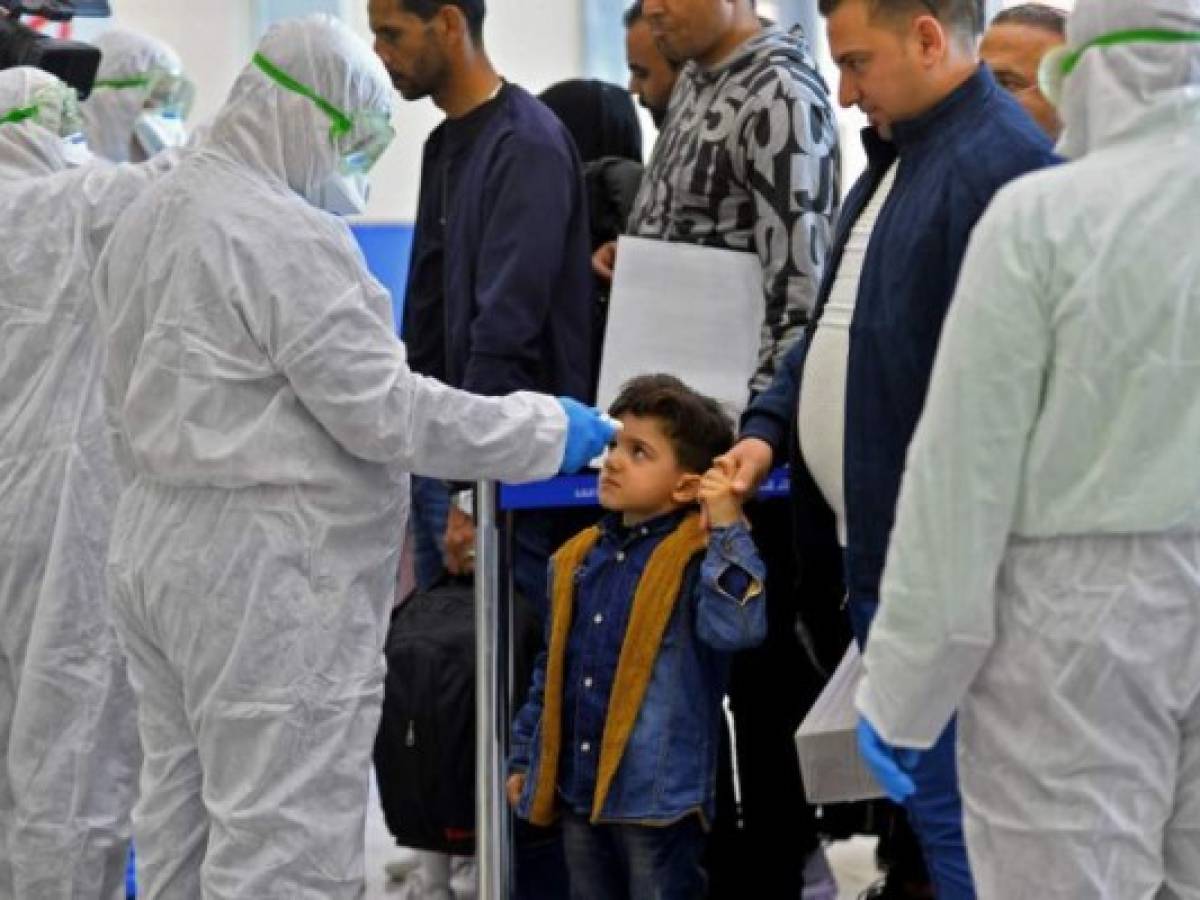 The body temperature of an Iraqi child returning from Iran is measured upon her arrival at the Najaf International Airport on February 21, 2020, after Iran announced cases of coronavirus infections in the Islamic republic. (Photo by Haidar HAMDANI / AFP)