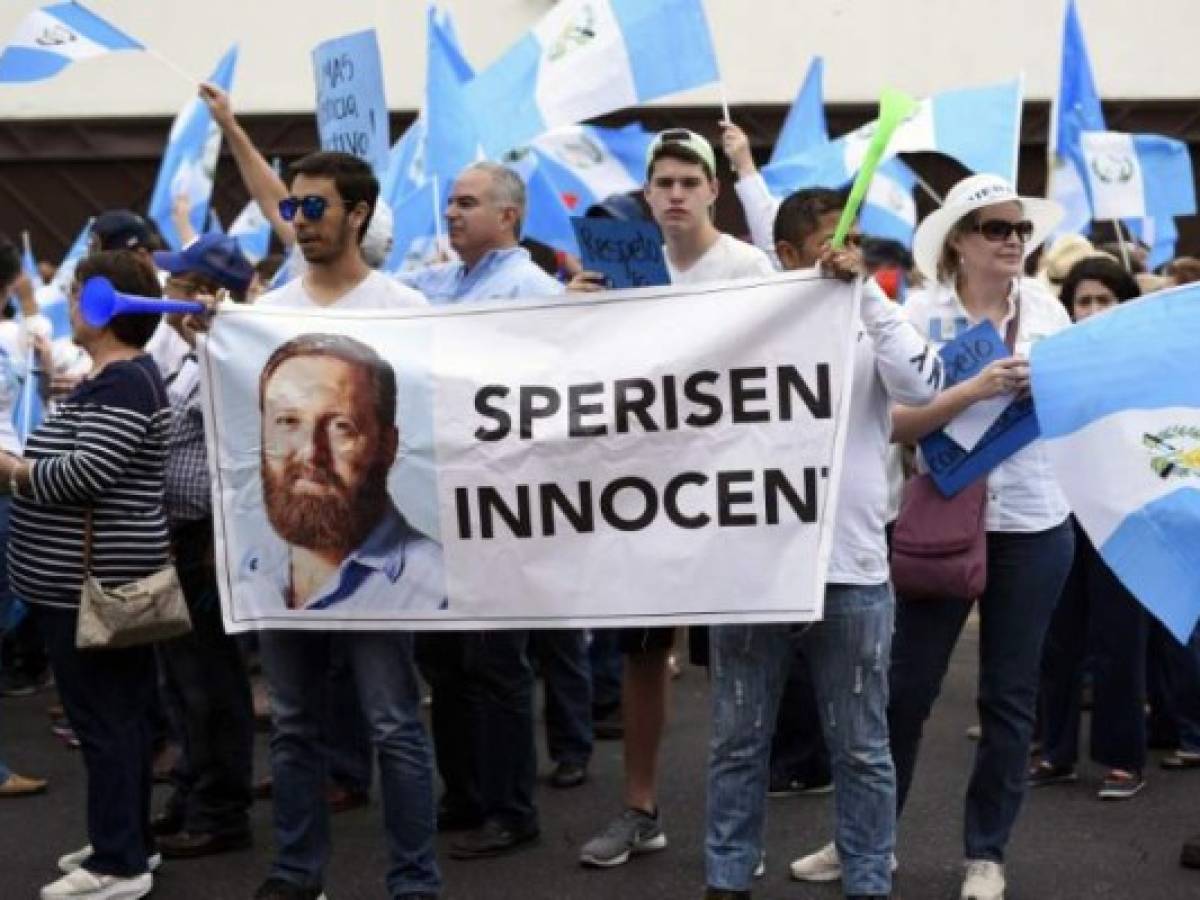 People hold a banner with an image of Guatemala's former police chief Erwin Sperisen during a protest against the head of the UN International Commission Against Impunity in Guatemala (CICIG), Colombian Ivan Velasquez, outside the CICIG headquarters in Guatemala City on May 5, 2018. / AFP PHOTO / JOHAN ORDONEZ
