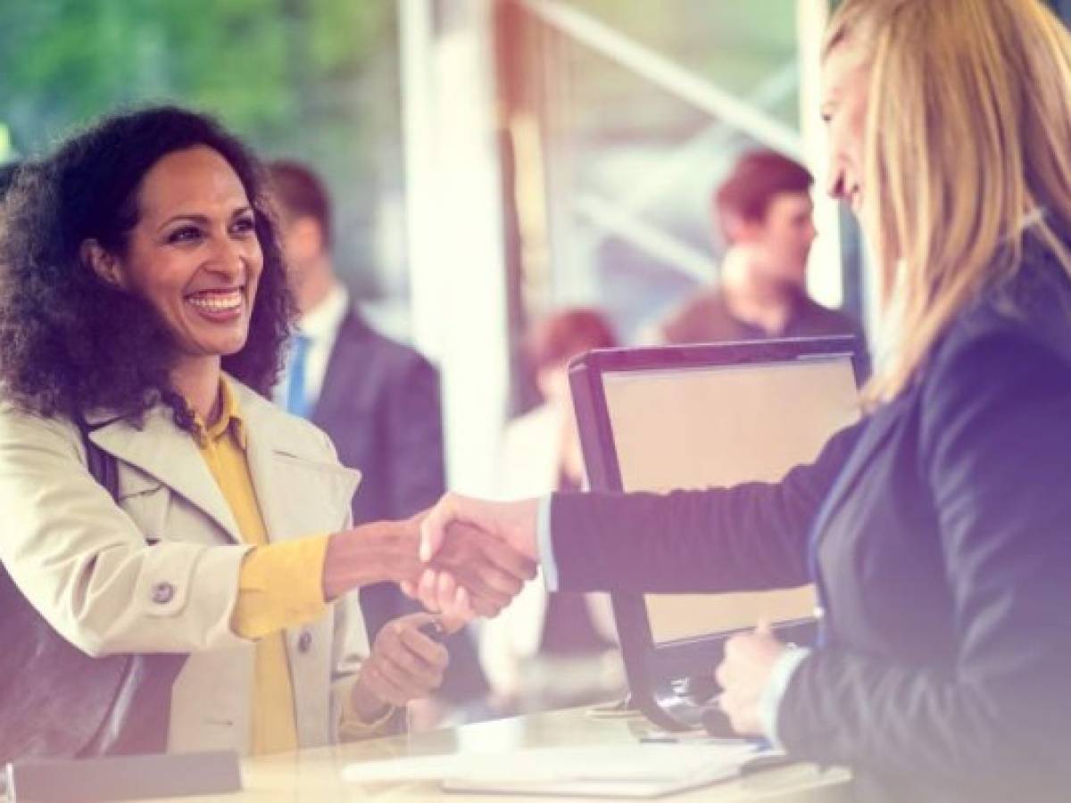 Customer shaking hands with bank teller at bank counter.