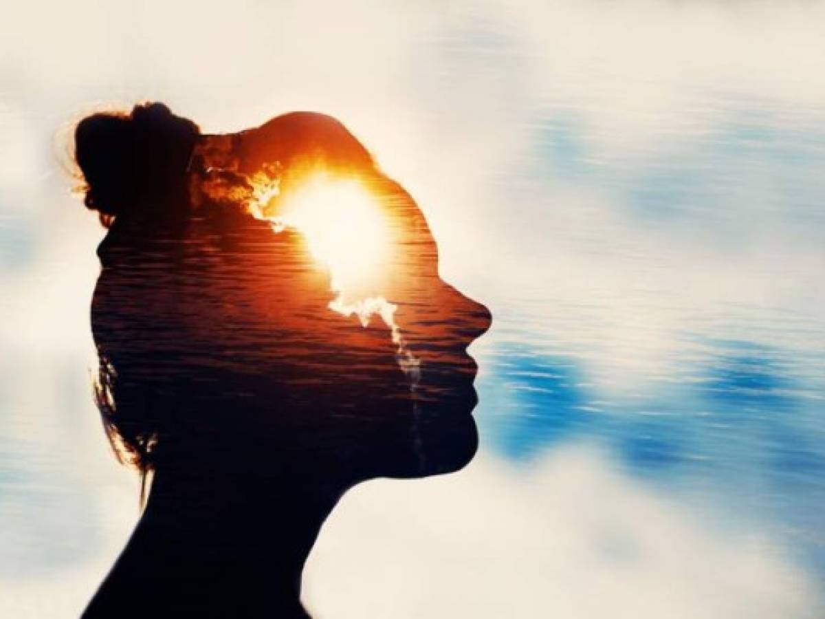 The Light Head. Silhouette of young woman on sky background with sun in her head.