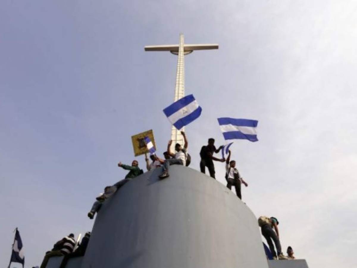 Nicaraguan Catholic faithful wave national flags as they stand atop the roof of the Metropolitan Cathedral in Managua, during an open air mass, to demand the end of violence in their country, on April 28, 2018.University students at the forefront of anti-government unrest in Nicaragua on Saturday issued conditions for talks with the government of President Daniel Ortega. The demands followed a week of protests and clashes with police that left at least 43 people dead, according to a leading human rights group. / AFP PHOTO / INTI OCON