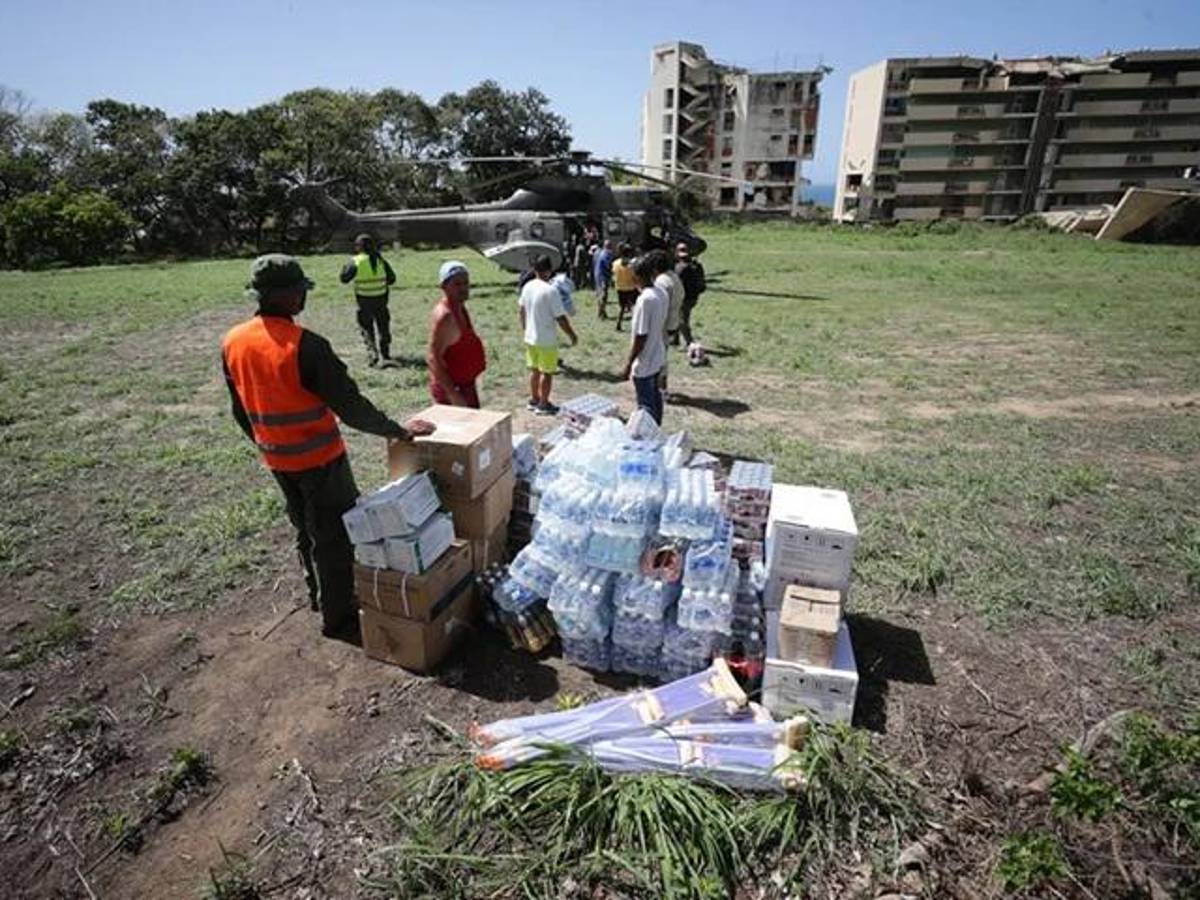Un grupo de voluntarios descargaa ayuda humanitaria de un helicóptero en La Guaira (Venezuela). EFE/ Ronald Peña R